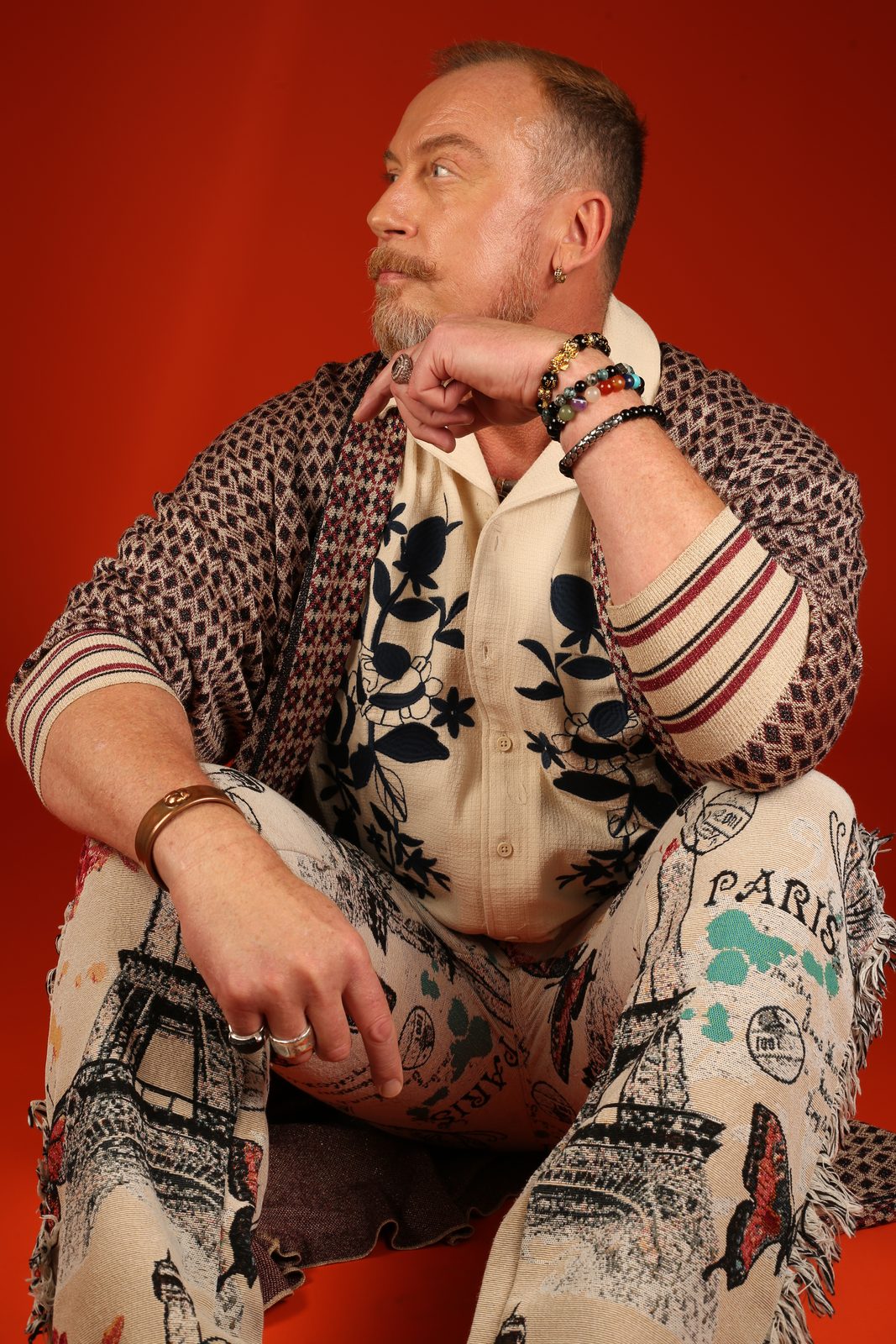 Ross Leslie Nicol seated in a patterned jacket against a warm orange background
